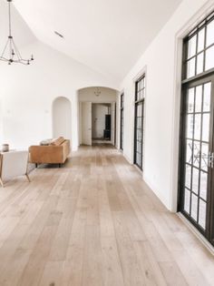 an empty living room with wood floors and large windows