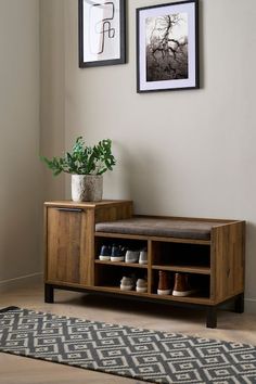 a wooden bench sitting next to a wall with pictures on it and a plant in the corner