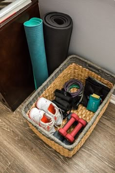 a basket filled with various items sitting on top of a wooden floor next to a wall