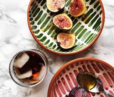 figs and ice tea are served in bowls on a marble countertop with green leaves