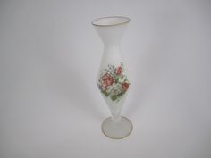 a white vase with red and pink flowers on the bottom is sitting against a white background