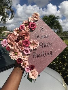 someone is holding up a pink graduation cap that says i know she's smiling