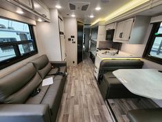 the interior of an rv with couches, tables and kitchen area in front of it