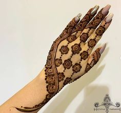 a woman's hand is decorated with henna and flowers on her left arm