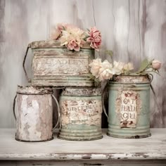 four old tin canisters with flowers in them