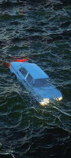 a car is floating in the middle of the ocean with red lights on it's hood