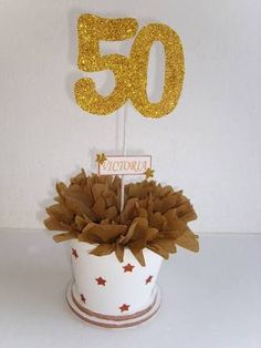 a 50th birthday cake topper sitting in a white cup with gold stars on it