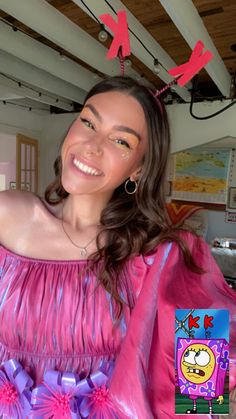 a woman in a pink dress is smiling at the camera and has red bows on her head