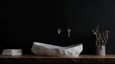 a bathroom with black walls and white towels on the counter next to a vase filled with flowers