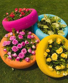 four different colored tires with flowers growing out of them on the grass in front of each other