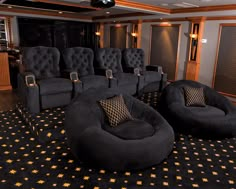 an empty theater room with black chairs and gold stars on the carpeted flooring