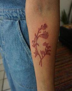 a tattoo on the arm of a person with flowers and leaves in red ink is shown