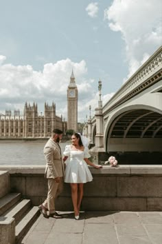 a man and woman standing next to each other in front of the big ben clock tower