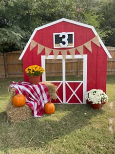 a red barn with hay bales and pumpkins