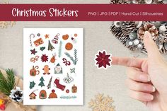 christmas stickers are being held up by someone's hand and surrounded by holiday decorations