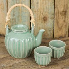 a tea pot and three cups on a table