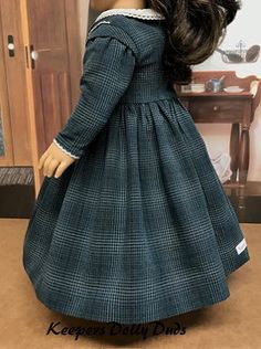 the doll is wearing a blue dress and white collared shirt with long sleeves,