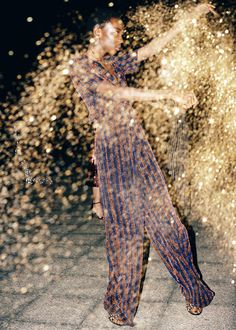 a woman standing in front of a firework display with her arms spread out to the side