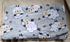 a blanket with sheeps on it is laying on the bed and has been made into a pillow