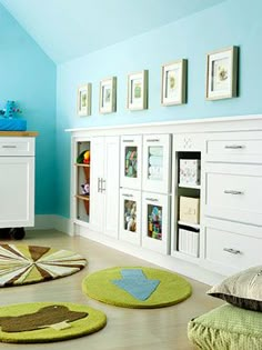 a child's bedroom with blue walls and green rugs on the floor in front of white cabinets