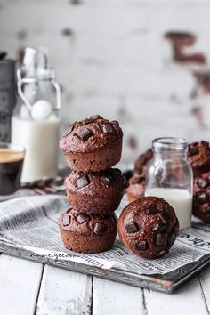 chocolate muffins stacked on top of each other next to a glass of milk