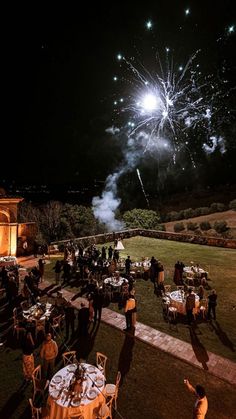 fireworks are lit up in the night sky above tables and chairs at an outdoor event