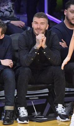 a man sitting next to a woman on top of a basketball court