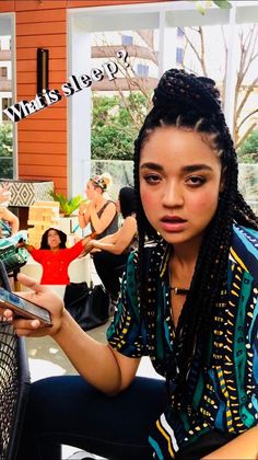 a young woman sitting on the ground looking at her cell phone and holding it in her hand