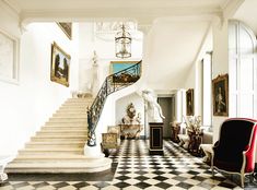 an ornate staircase in the middle of a room with black and white checkered flooring