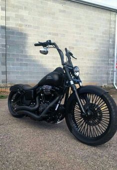 a black motorcycle parked in front of a brick building with no one on it's bike