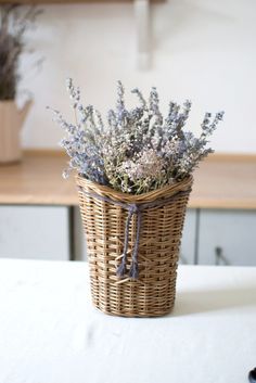 a wicker basket with lavender flowers in it on a white tableclothed surface