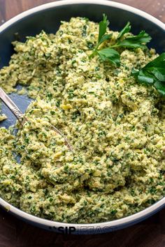 a bowl filled with green food on top of a wooden table