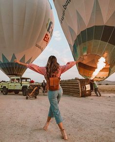 a woman standing in front of two hot air balloons