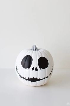 a white pumpkin decorated with black eyes and a jack - o'- lantern face