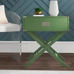 a green side table with a plant on it and a white chair in the background