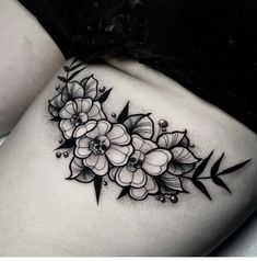 a black and white photo of flowers on the side of a woman's thigh