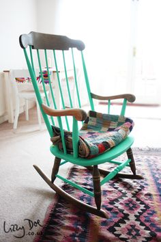 a green rocking chair sitting on top of a rug