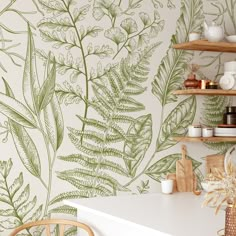 a kitchen with green leaves on the wall and shelves above it, next to a white counter