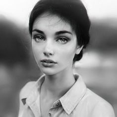 a black and white photo of a woman with short hair wearing a shirt looking at the camera