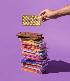 a stack of books being held by a person's hand with a gold card on top