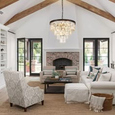 a living room filled with furniture and a chandelier hanging from the ceiling over a fire place