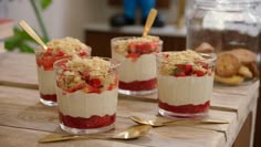 three desserts with strawberries and crumbs in small glasses on a wooden table