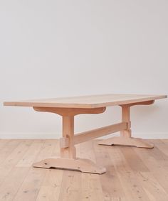 a wooden table sitting on top of a hard wood floor next to a white wall