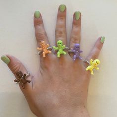 a woman's hand with five rings on it and four small toy bears attached to the ring