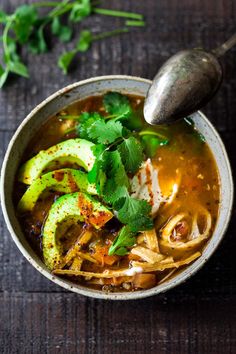 an overhead view of a bowl of soup with avocado and cilantro