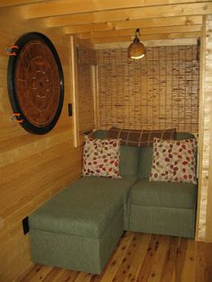 a green couch sitting in the corner of a living room next to a wooden wall