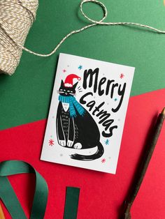 a christmas card with a black cat wearing a santa hat and scarf on top of it