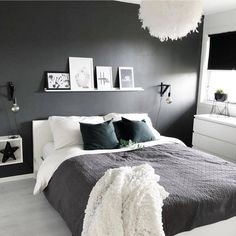 a bedroom with gray walls and white bedding, pictures on the wall above the bed