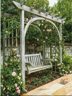 a wooden bench sitting under a pergoline covered in pink flowers and greenery