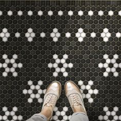 a person standing in front of a black and white tile floor with hexagonal tiles